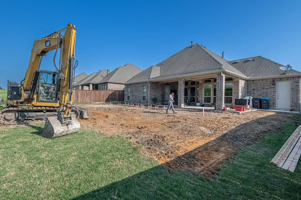 A bare graded back yard in Upper St. Clair with an excavator parked on the cut