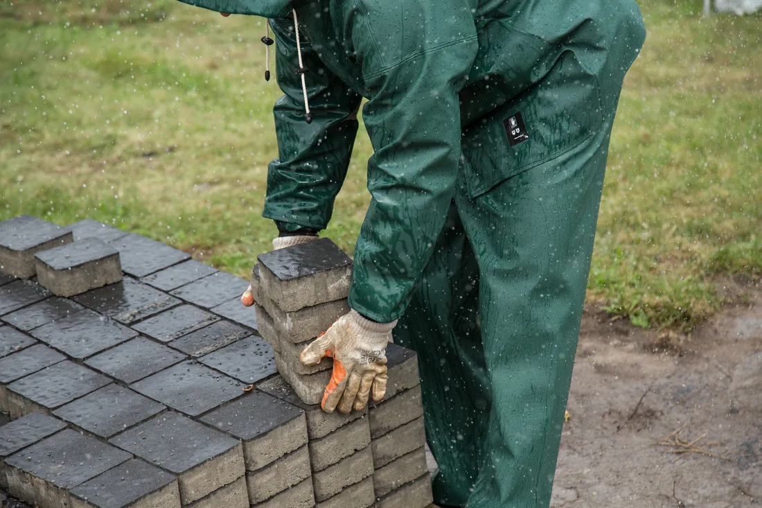 A crew member laying paving stones by hand