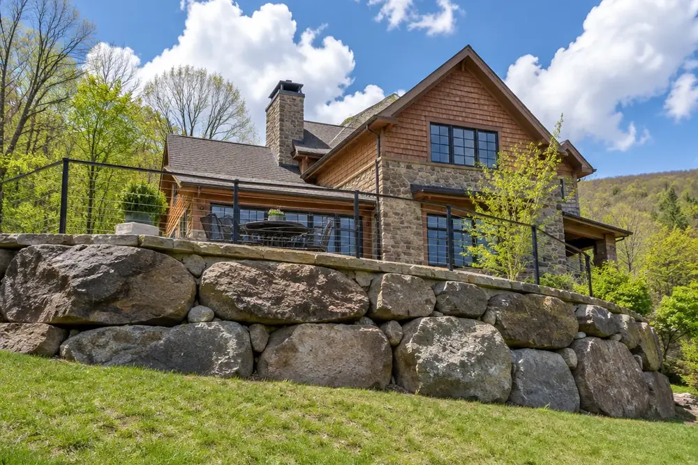 A stone terrace carried on a boulder-faced retaining wall above a grass bank on a bright spring day