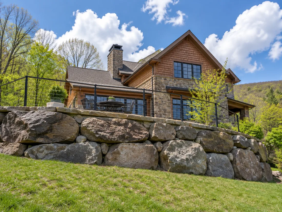 A stone terrace carried on a boulder-faced retaining wall above a grass bank